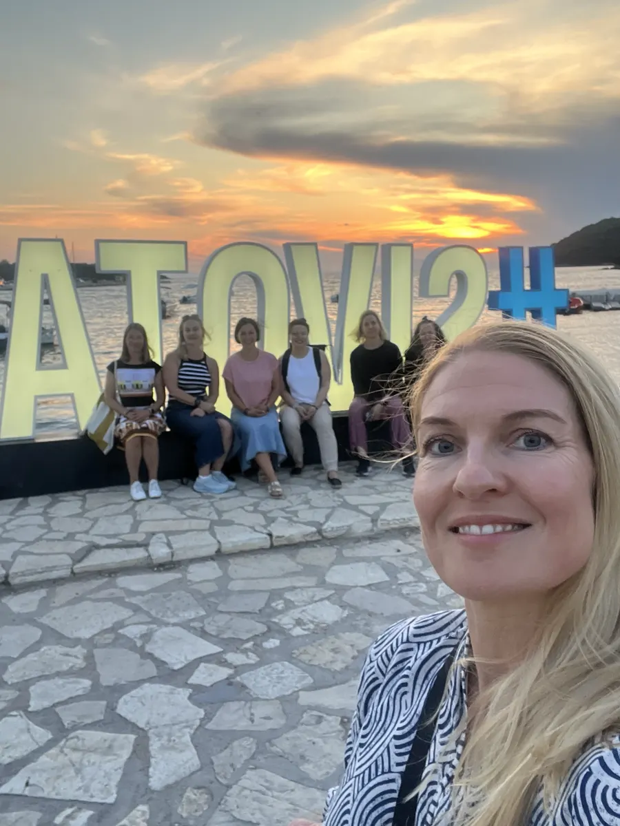 Ryhmäkuva Sivotan kyltin edessä auringonlaskussa